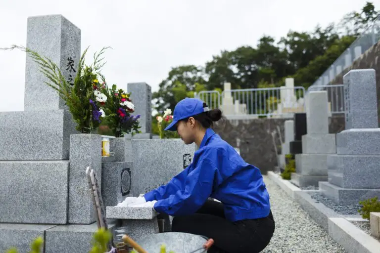 お墓掃除をする作業服の女性